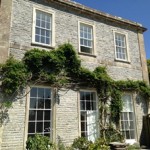 Old traditional country townhouse with trailing ivy hanging plant and restored white sash windows