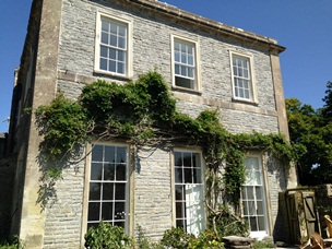 Old traditional country townhouse with trailing ivy hanging plant and restored white sash windows